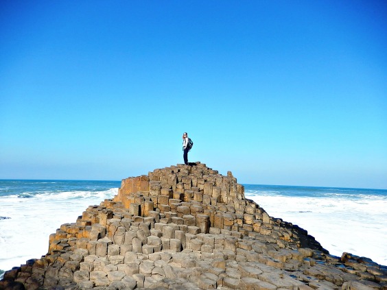 Girl standing on basalt pillars at Giant's Causeway, Northern Ireland